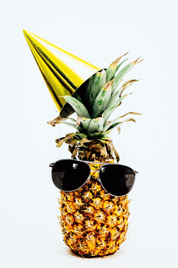 A pineapple dressed in sunglasses and a party hat, exuding a fun and tropical vibe.